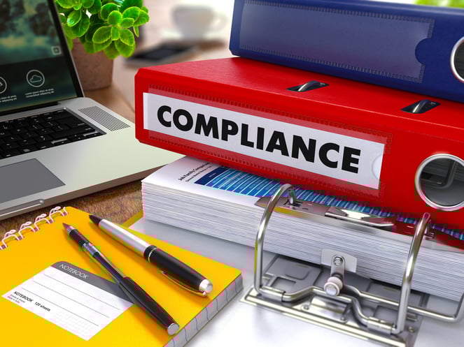 Red Ring Binder with Inscription Compliance on Background of Working Table with Office Supplies