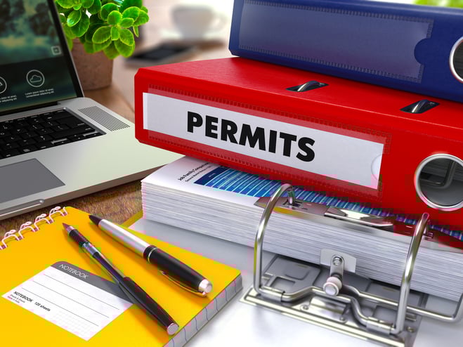 Red Ring Binder with inscription Permits on Background of Working Table with Office Supplies