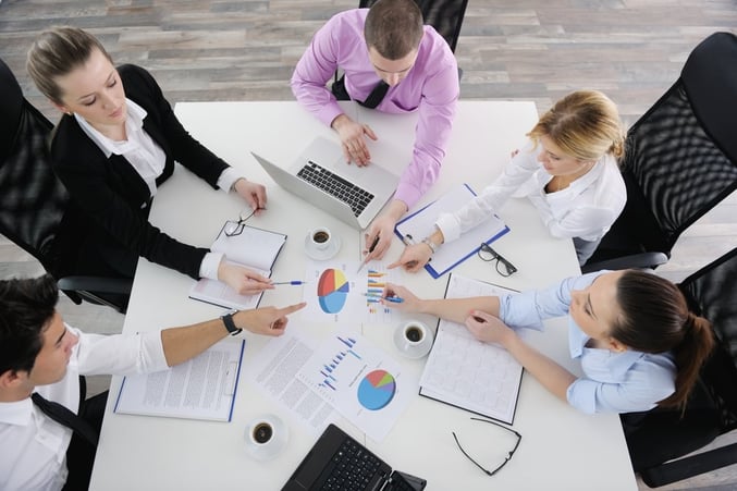 Group of young business people sitting in board room during meeting and discussing with paperwork.