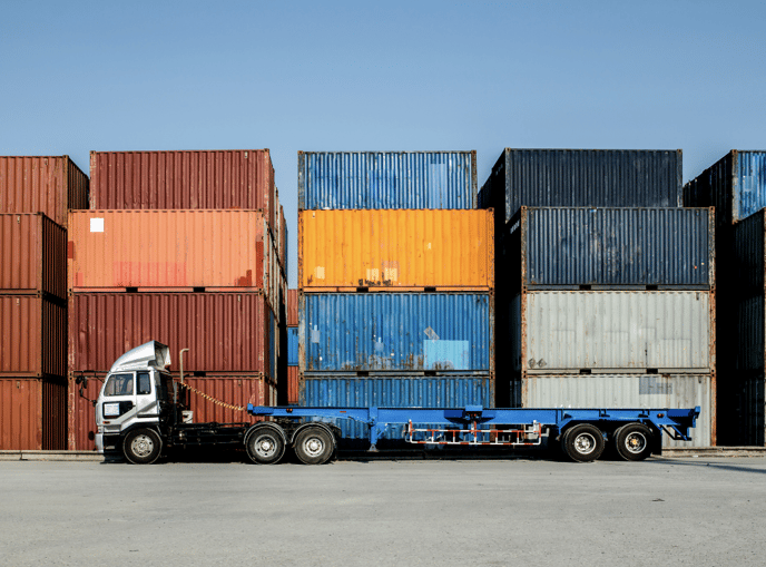 A flat bed truck in a container yard.