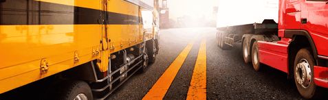 A yellow and red truck driving passed each other