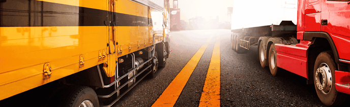 A yellow and red truck driving passed each other